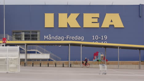 Ein-Radfahrer-Fährt-Unter-Riesigen-IKEA-Briefen-Auf-Einem-Leeren-Parkplatz-Hindurch