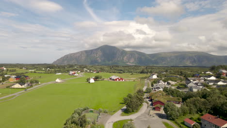 Blick-Auf-Ländliche-Häuser-Mit-Wunderschöner-Grüner-Bauernlandschaft-Und-Bergen-In-Der-Ferne-In-Hustad,-Norwegen