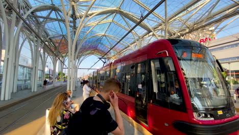 Slow-motion-shot-of-tram-arriving-tramway-station-in-Lodz-during-sunny-day---People-entering-and-wearing-face-mask-during-covid-19-pandemic-in-Poland