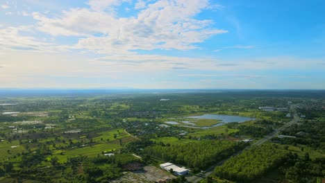 Aerial-view-moving-and-seeing-swamp-countryside-with-the-road-a-sunny-day-in-Khonkaen,-Thailand