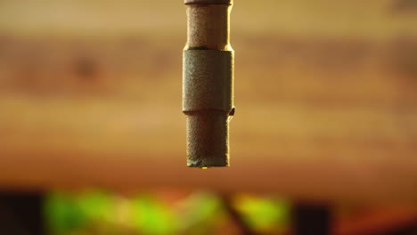 Old-vintage-looking-tap-dripping-water-drops-with-light-reflection-against-wooden-background,-close-up-view