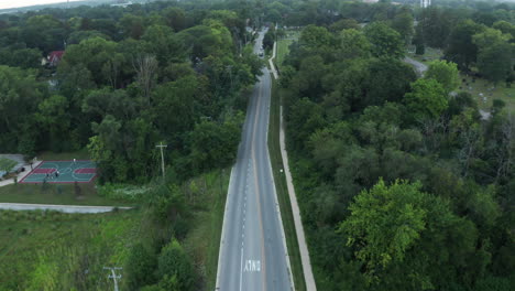 Elevated-aerial-footage-following-a-car-as-it-travels-down-a-suburban-neighborhood-of-America