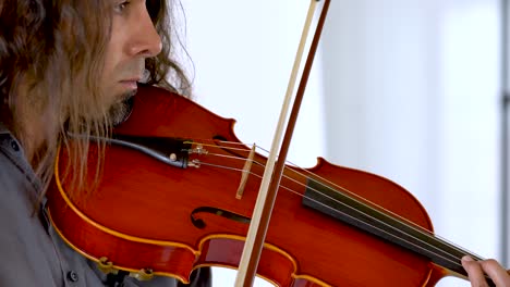 Close-up-profile-of-hispanic-male-musician-with-long-hair-and-goatee-playing-red-viola
