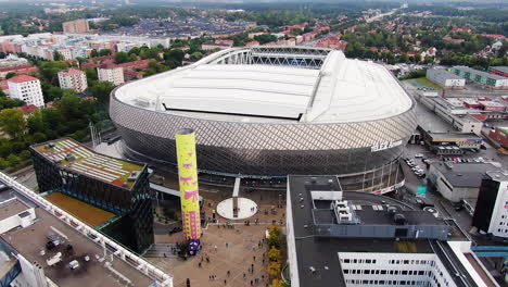 City-buildings-and-massive-arena-of-Tele2-in-Stockholm,-aerial-tilt-up-view