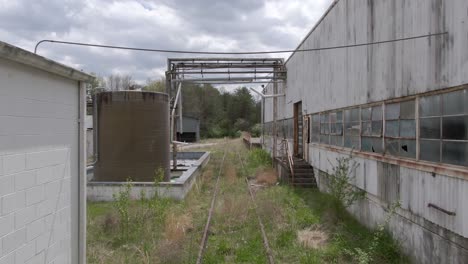Drone-Footage-Dollying-Forward-Over-Overgrown-Train-Tracks-in-an-Abandoned-Factory