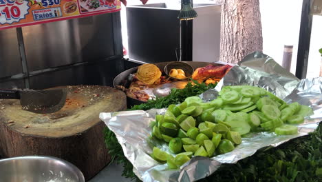 Mexican-street-food-stand-with-meat-on-grill,-chopping-board,-limes-and-vegetables-for-preparing-delicious-tacos