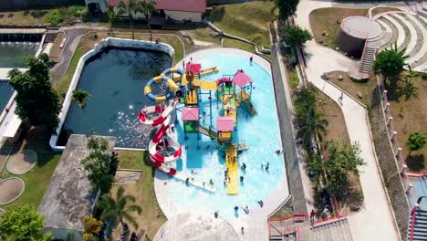 Aerial-view-of-children-playing-on-water-slide-in-Kalibening,-Java,-Indonesia