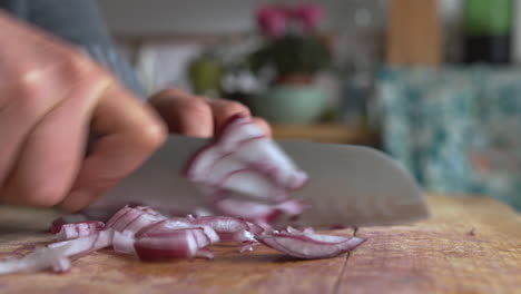 Close-up-woman's-hand-fast-chopping-in-pieces-Italian-red-onions-with-a-rounded-sharp-knife-in-the-kitchen