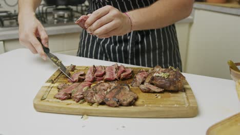 Chef-cuts-beef-steak-into-slices-on-wooden-cutting-board