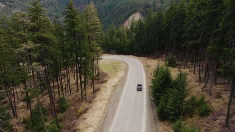 Aerial-view-of-black-truck-driving-along-road-in-British-Columbia,-Canada