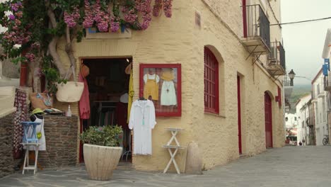 Pequeña-Y-Antigua-Tienda-Con-Vestidos-Y-Accesorios-Femeninos-Expuestos-En-El-Exterior-En-Cadaqués,-Cataluña,-España
