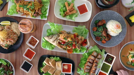 Male-hand-picking-up-pork-pieces-and-condiments-from-thai-cuisine-food-flat-lay