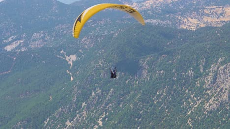 Paragliders-fly-over-mountain-top-in-epic-scenery
