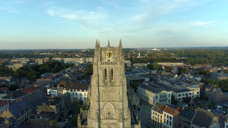 Basilica-of-Our-Lady-in-Tongeren,-Clock-Tower-Close-Up-Drone-Pull-Back