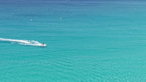 Water-bike-speeding-through-crystal-clear-water-of-Mediterranean-sea,-aerial-drone-view