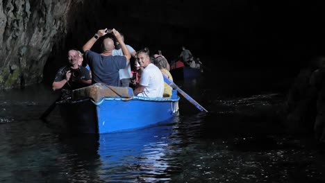 Male-Tourists-Taking-Pictures-At-Cave-From-Boat-Cruising-At-Melissani-Lake-In-Kefalonia,-Greece