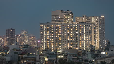 Day-to-night-time-lapse-in-densely-populated-urban-area-with-artificial-electric-lights-coming-on-in-illuminated-buildings