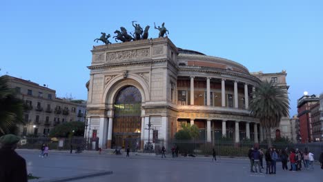 Historisches-Gebäude-Des-Teatro-Politeama-Garibaldi-In-Palermo,-Sizilien-In-Der-Abenddämmerung-Mit-Menschen-In-Der-Nähe