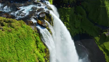 Seljalandsá-river-falling-down-as-Seljalandsfoss-waterfall-and-creating-a-Rainbow-in-Iceland---rotating-Aerial-shot