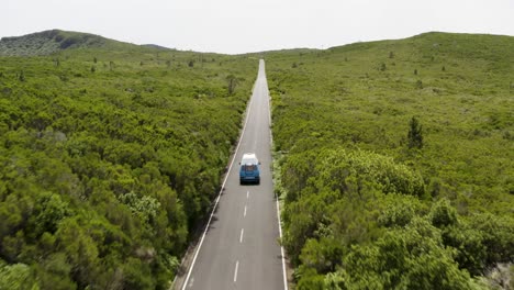 Beautiful-aerial-shot-following-a-VW-Camper-van-on-a-scenic-road-during-daytime-on-Madeira,-Portugal