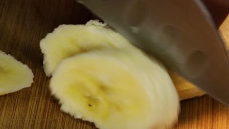 Sharp-knife-cuts-slices-of-a-peeled-banana,-macro-shot-detail-close-up-in-4k