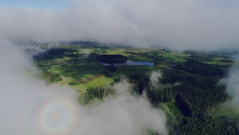 Drone-shot-of-beautiful-green-rural-landscape-through-white-clouds-on-a-sunny-day