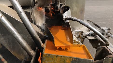 Closeup-Of-Hot-Orange-Thermoplastic-Paint-Dripping-On-A-Line-Marker-Machine