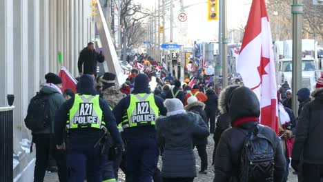 Bewaffnete-Polizisten-Gehen-Bei-Einem-Freiheitskonvoi-Marsch-In-Ottawa,-Kanada,-Neben-Friedlichen-Demonstranten