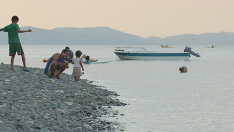 Asian-Father,-Daughter-And-Other-People-Playing-In-A-Rocky-Shore