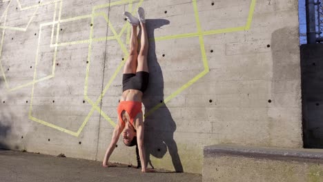Young-fit-woman-kicks-up-into-handstand-against-wall