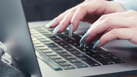 Secretary-hands-with-long-nails-typing-on-modern-keyword-laptop-device,-close-up-slow-motion-of-caucasian-female-working-online