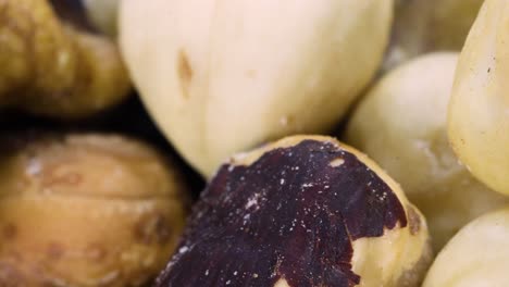 Macro-shot-of-a-trail-mix:-hazelnuts,-almonds,-walnuts-rotating-over-a-black-surface