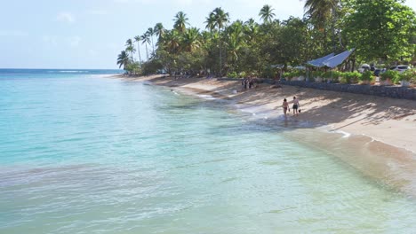 Tourists-walking-along-Playa-Punta-Popy-seashore,-Las-Terrenas-in-Dominican-Republic