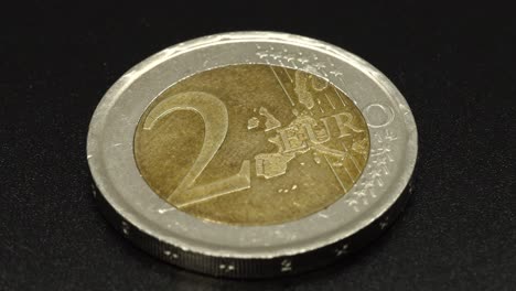 Eine-Glänzende-Zwei-Euro-Münze,-Die-Sich-Auf-Schwarzem-Hintergrund-In-4K-Dreht