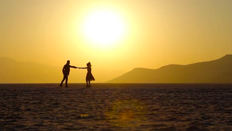 Recently-engaged-couple-dancing-on-a-scenic-yellow-sunset-with-a-big-sun-landscape-in-the-horizon