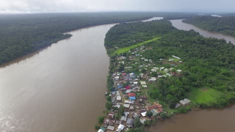 Aerial-drone-footage-flying-over-remote-village-alongside-the-river-in-South-America