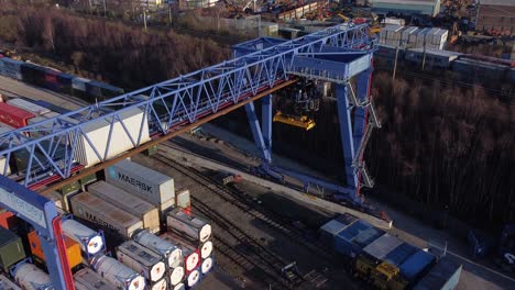Shipping-container-crane-lift-unloading-heavy-cargo-export-crate-containers-in-shipyard-aerial-view-flyover-shot