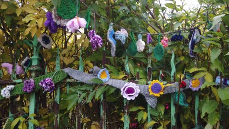 Close-up-of-knitted-flowers-on-a-green-park-gate