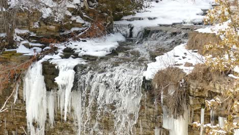 Frozen-Niagara-Escarpment-waterfall-cascades-falling-from-icy-creek-in-Hamilton,-Ontario,-Canada