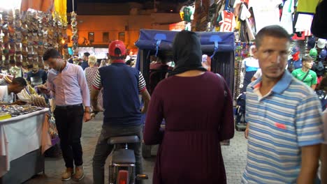 Walking-through-night-markets-in-Marrakesh-Morocco-exploring-the-local-culture,-busy-crowds-with-lots-of-people