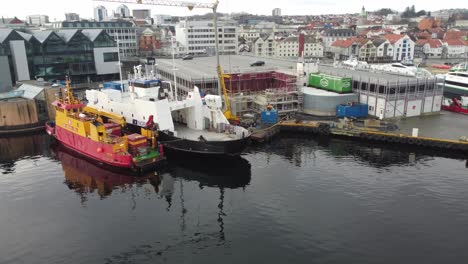 Norled-ferry-Sveio-and-Amundsen-diving-vessel-Basen-is-moored-alongside-in-Stavanger-harbor---Aerial-rotating-around-vessels-in-port