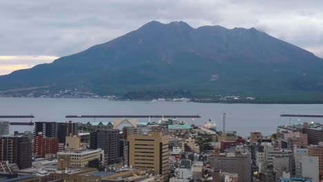 Der-Vulkan-Sakurajima-Und-Die-Skyline-Der-Stadt-Kagoshima-Am-Abend,-Südjapan