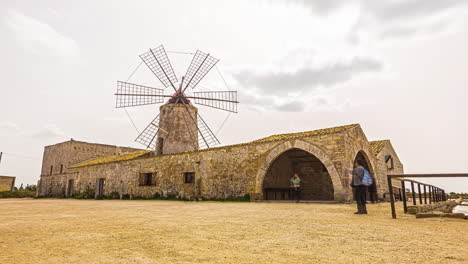 Tourist-visiting-old-building-with-Windmill-Tower-during-cloudy-day-on-Sicily-Island-in-Italy,Europe---Time-lapse-shot