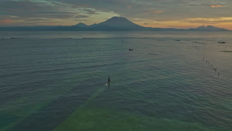 Local-farmers-harvesting-seaweed-in-shallows-at-Pasir-Putih-Beach-during-sunrise,-Mount-Agung