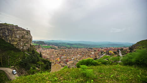 Time-lapse-shot-of-idyllic-view-from-Chiesa-Maria-SS-del-Malpasso-on-Corleone-Town-during-dense-clouds-at-sky---Silhouette-of-mountain-range-in-background