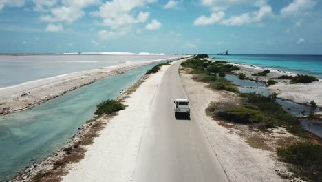 Drone-view-from-behind-a-car-going-to-the-Salt-pans,-in-Bonaire,-the-Dutch-Caribbean,-in-South-America