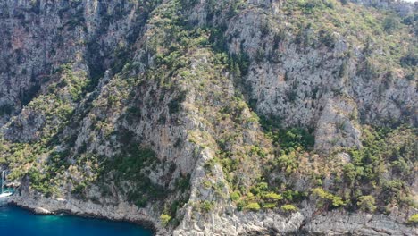 aerial-drone-circling-large-green-mountain-cliffs-around-Butterfly-Valley-in-Fethiye-Turkey-on-a-sunny-summer-day