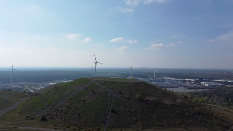 Renewable-energy-wind-turbines-behind-mining-heap-in-Belgium,-aerial-view