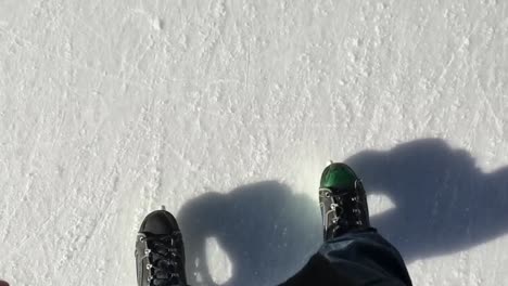 Ice-skates-on-the-ice-field,-ice-skater-point-of-view-looking-down-at-his-own-feet
