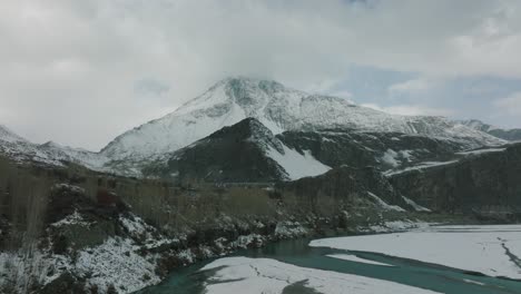 Luftwagen-über-Dem-Hunza-Fluss-Mit-Blick-Auf-Den-Epischen-Schneebedeckten-Berg-In-Der-Ferne
